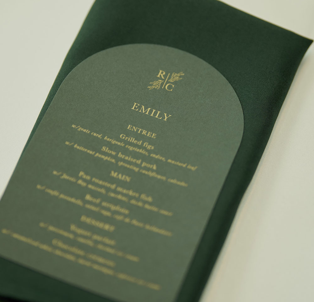 Dark green and metallic gold wedding menu with dark green napkin