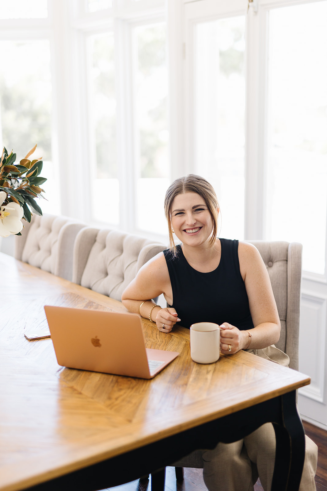 Ashleigh at desk with laptop and a cup of tea looking at the camera with a friendly smile