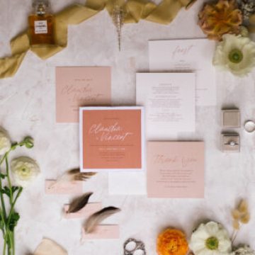 flat lay of wedding invitation suite with orange and white coloured cards surrounded with flowers and silk ribbon. Custom Wedding Invitations and Stationery