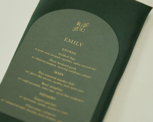 Dark green and metallic gold wedding menu with dark green napkin