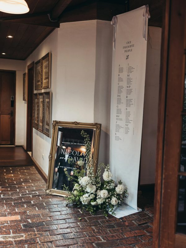 mirror wedding welcome sign styled at wedding reception with linen seating plan and flowers